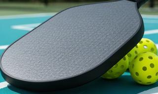 Graphite Hurricane pickleball paddle with textured face on an outdoor court