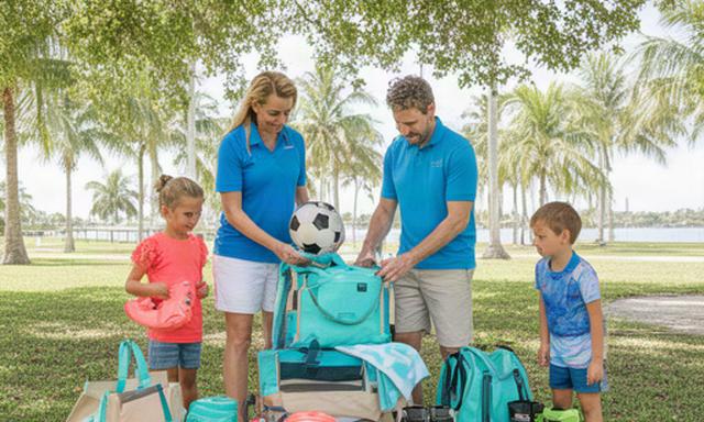 North Palm Beach family arranging beach and youth sports gear beside a shaded park