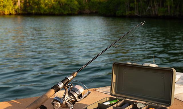 Light tackle fishing rod and tackle box beside a South Florida inlet