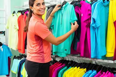 Smily Ferahtia, head buyer, arranging colourful multi-sport apparel on shop rails